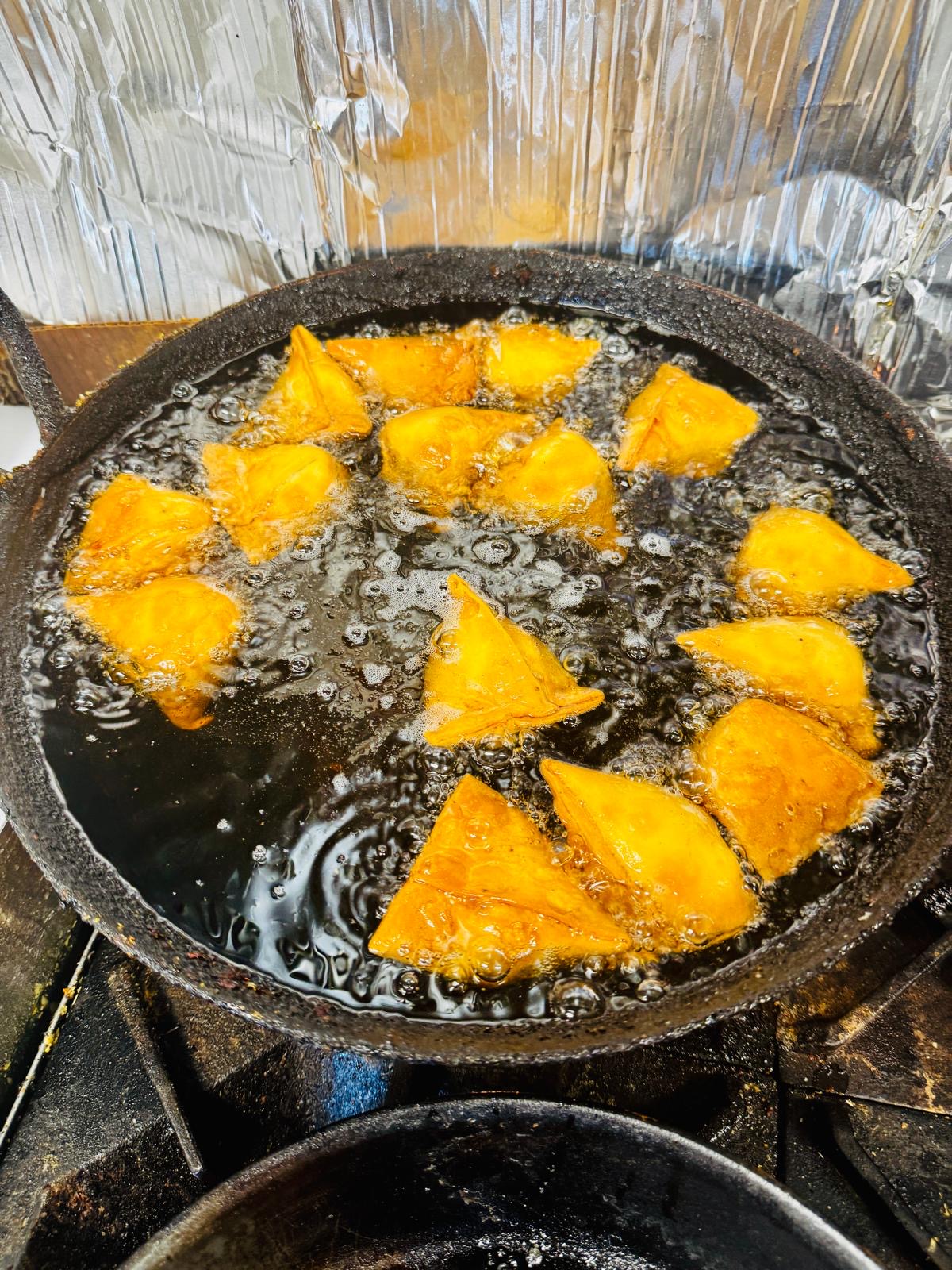 Fresh samosas frying for a catering order