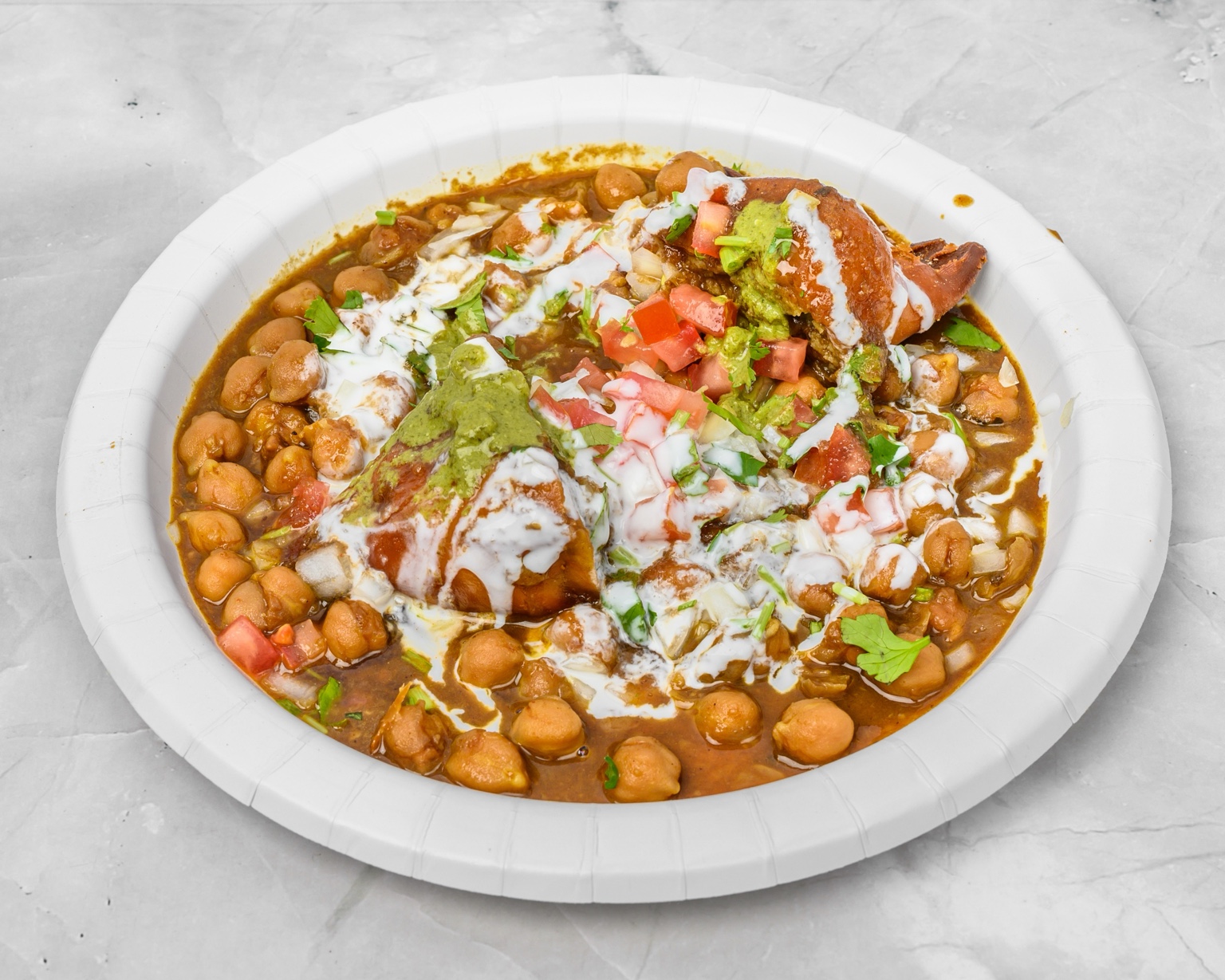 Samosa chaat with chickpeas, yogurt, chutneys, tomato and cilantro